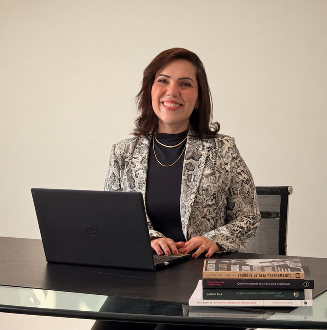 Líscia Carina à mesa de trabalho, com computador e livros